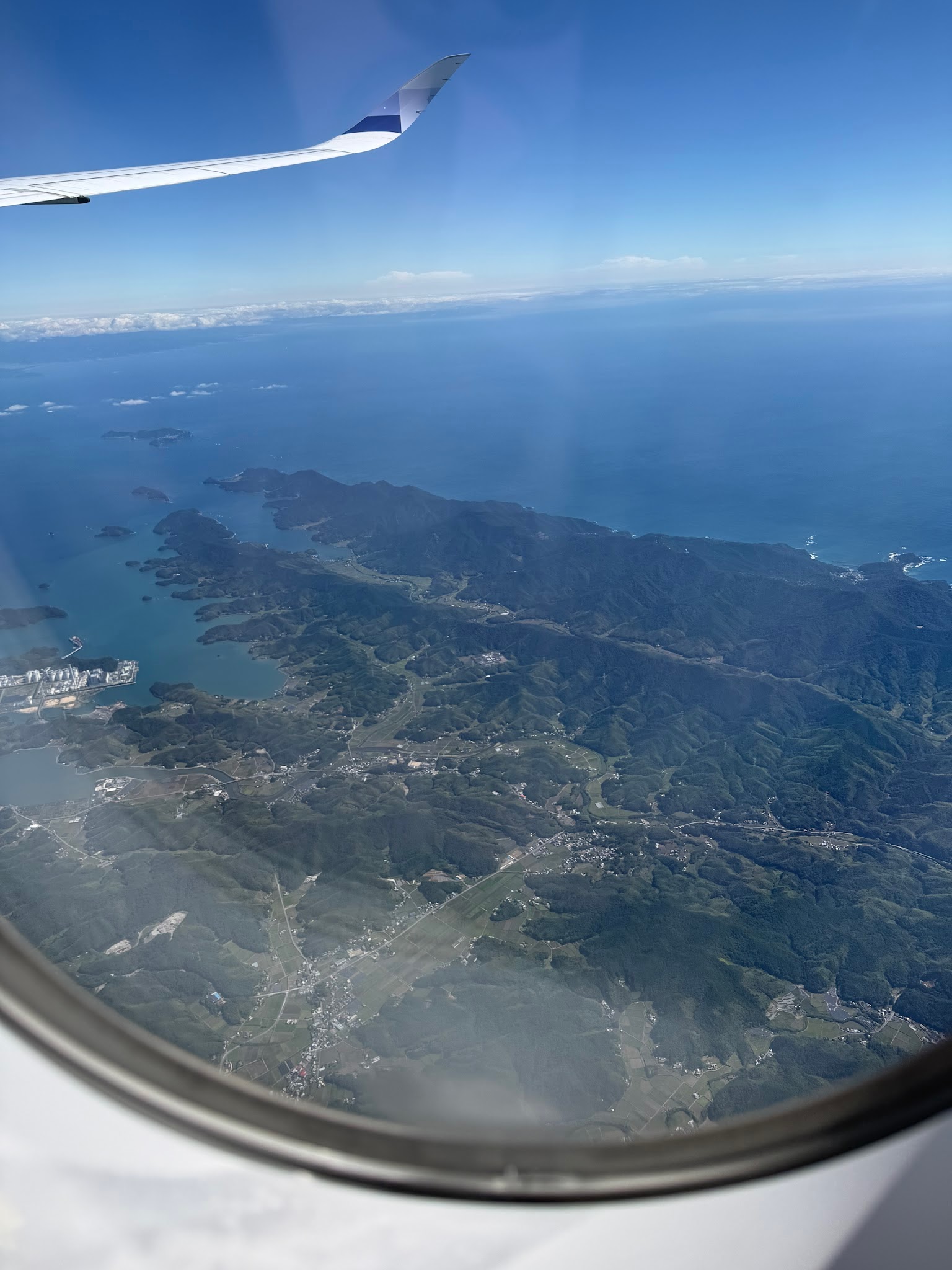 從飛機窗外俯瞰日本列島、海岸與雲層